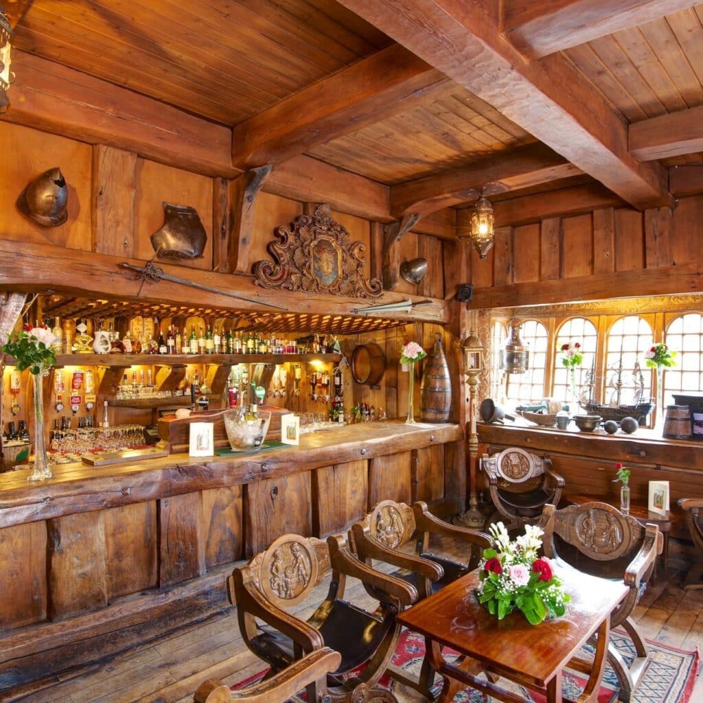 Atmospheric interior shot of the Armada Bar with salvaged oak beams and candlelight.
